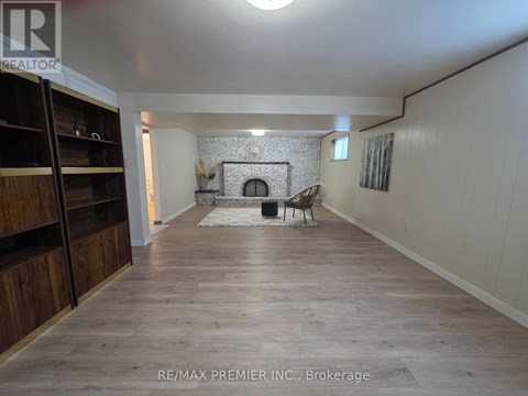 A spacious room with a fireplace and wooden flooring.