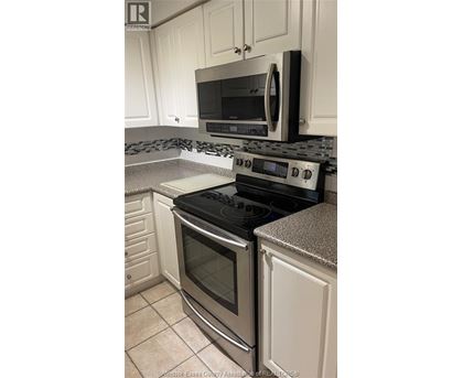 A kitchen with a black stove top oven and microwave above it.