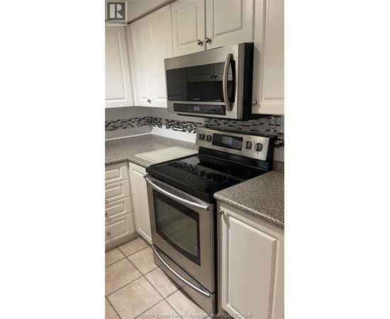 A kitchen with a black stove top oven and microwave above it.