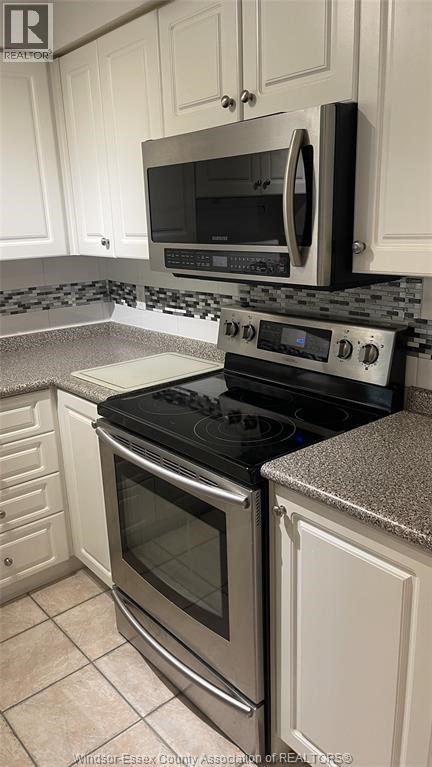 A kitchen with a black stove top oven and microwave above it.