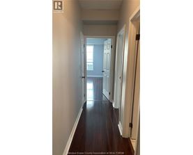 A long hallway with white walls and wood floors.