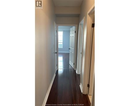 A long hallway with white walls and wood floors.