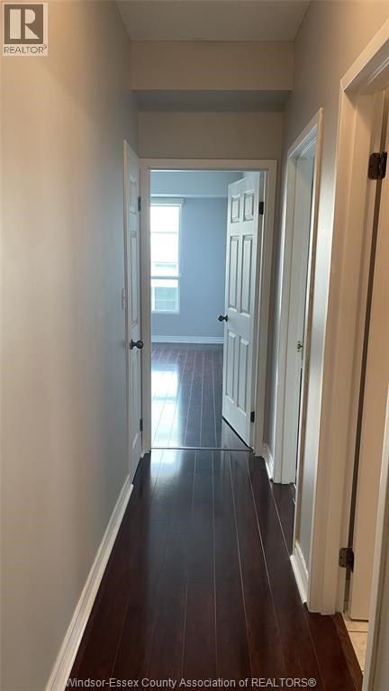 A long hallway with white walls and wood floors.