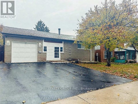 A house with a garage and a tree in front of it.