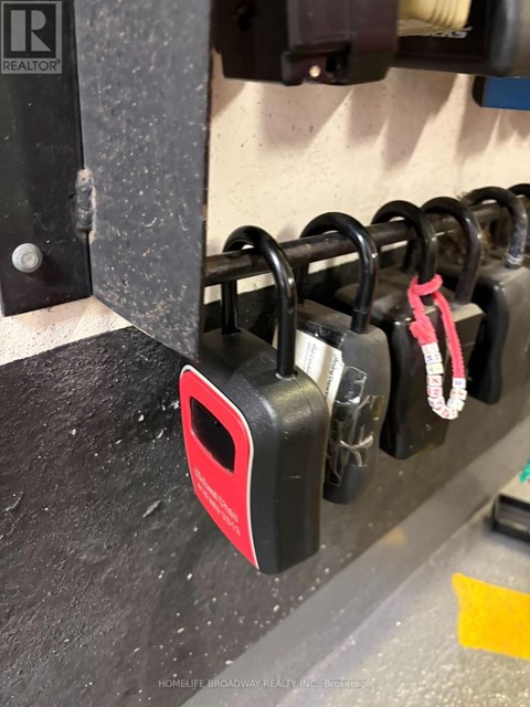 A red padlock is hanging on a black metal hook.