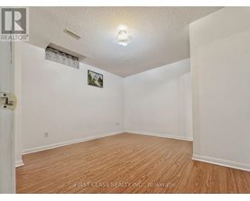 A room with wooden flooring and white walls, with a picture hanging on the wall.
