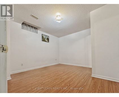 A room with wooden flooring and white walls, with a picture hanging on the wall.