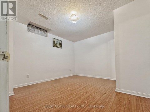 A room with wooden flooring and white walls, with a picture hanging on the wall.