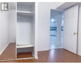 A bedroom with a white door and a white bench in the corner.