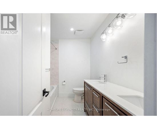 A bathroom with a toilet, sink, and lights.