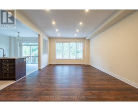 A spacious room with wooden flooring and a large window.