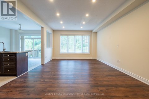 A spacious room with wooden flooring and a large window.