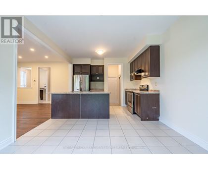 A spacious kitchen with dark brown cabinets and white tiled flooring.