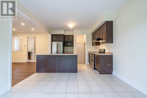 A spacious kitchen with dark brown cabinets and white tiled flooring.