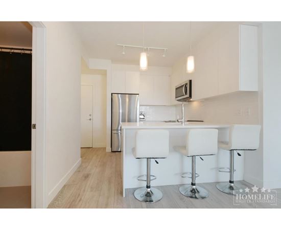 A kitchen with white chairs and a bar stool.