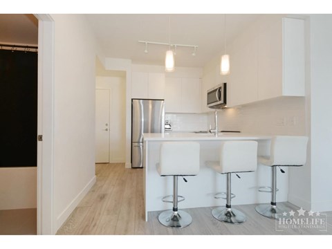 A kitchen with white chairs and a bar stool.