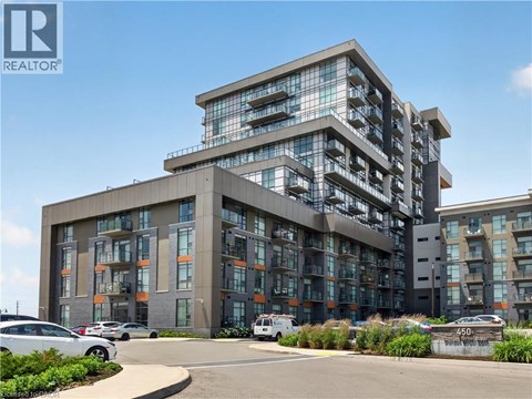 A modern multi-story building with a parking lot in front.