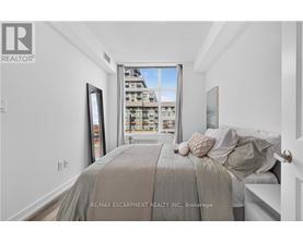 A bedroom with a large bed and a view of a building outside the window.
