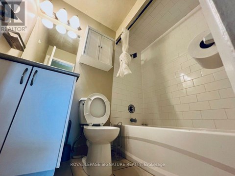 A white toilet sits in a bathroom with white tiles.