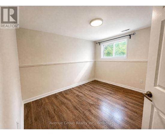 A room with wooden flooring and a window with blinds.