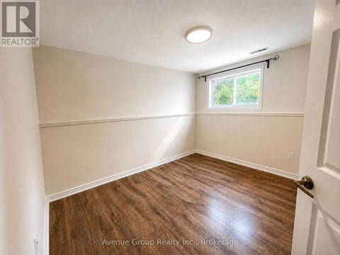 A room with wooden flooring and a window with blinds.