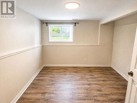 A spacious room with wooden flooring and a window.