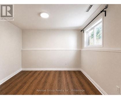 A spacious room with wooden flooring and a window letting in natural light.