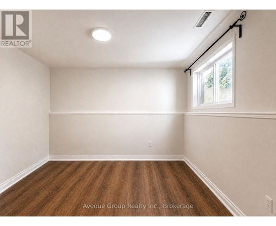 A spacious room with wooden flooring and a window letting in natural light.