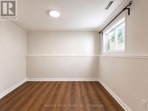 A spacious room with wooden flooring and a window letting in natural light.