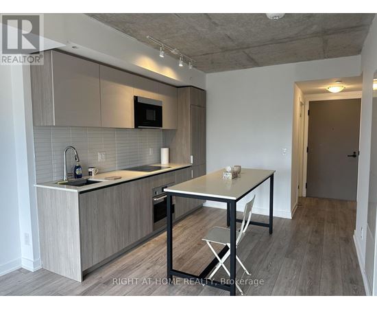 A kitchen with a table and chairs in the foreground and a doorway leading to another room in the background.