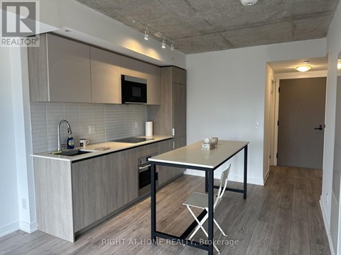 A kitchen with a table and chairs in the foreground and a doorway leading to another room in the background.
