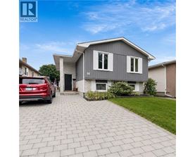 A modern house with a grey exterior and a red car parked in front.