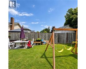 A backyard with a swing set and a table with chairs.