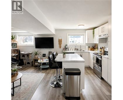 A modern kitchen with a white island and black bar stools.