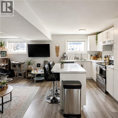 A modern kitchen with a white island and black bar stools.