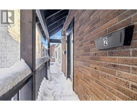 A snow-covered balcony with a brick wall and a sign that reads "2".