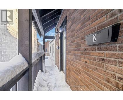 A snow-covered balcony with a brick wall and a sign that reads "2".