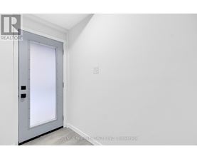 A grey door with a window in the middle is in a white room.