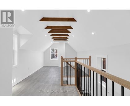 A spacious room with a wooden staircase and white walls.