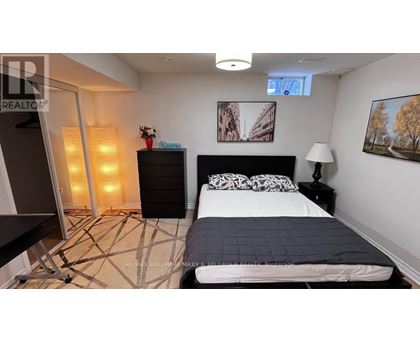 A bedroom with a large bed, a black dresser, and a painting on the wall.