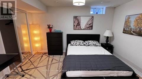 A bedroom with a large bed, a black dresser, and a painting on the wall.