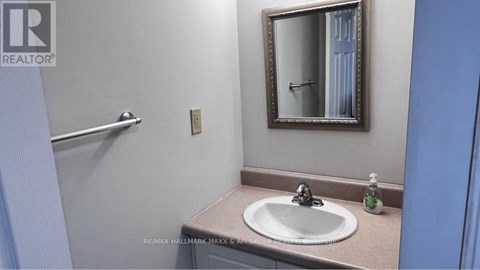 A bathroom with a sink, mirror and towel rack.