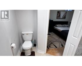 A white toilet in a small bathroom with a doorway leading to another room.