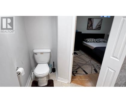 A white toilet in a small bathroom with a doorway leading to another room.