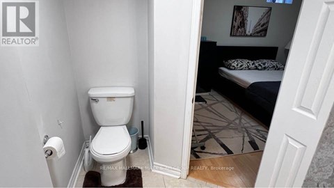 A white toilet in a small bathroom with a doorway leading to another room.