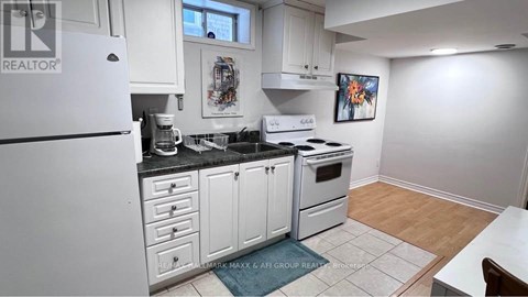 A kitchen with white cabinets and appliances, a fridge, a stove, and a dining table.