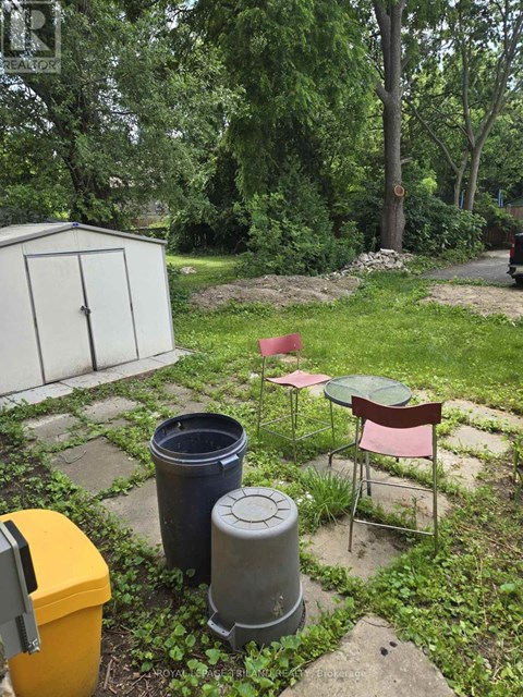 A backyard with a chair, table, and trash cans.