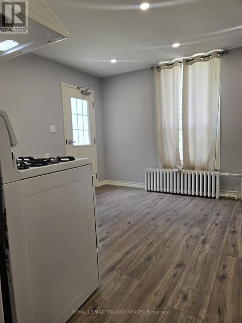 A kitchen with a white stove top oven and a window with white curtains.