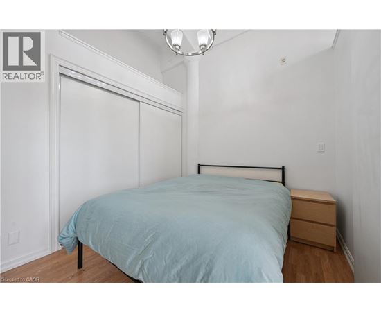 A bedroom with a bed, nightstand, and a lamp.