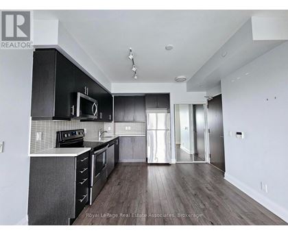 A modern kitchen with dark wood floors and white walls.